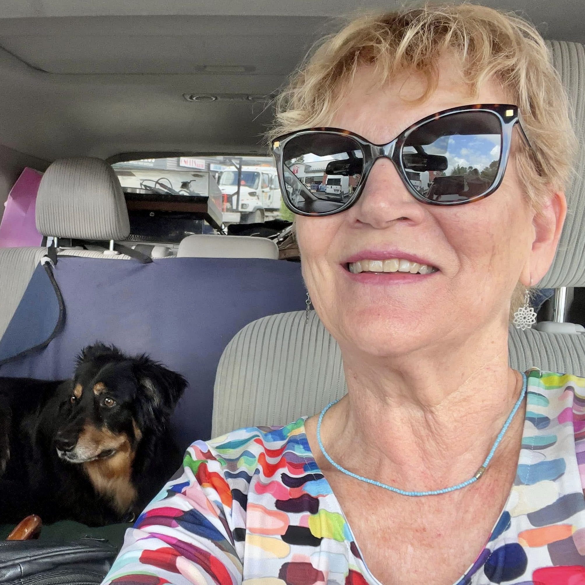 Patricia Morris smiling in the car with her dog Dali